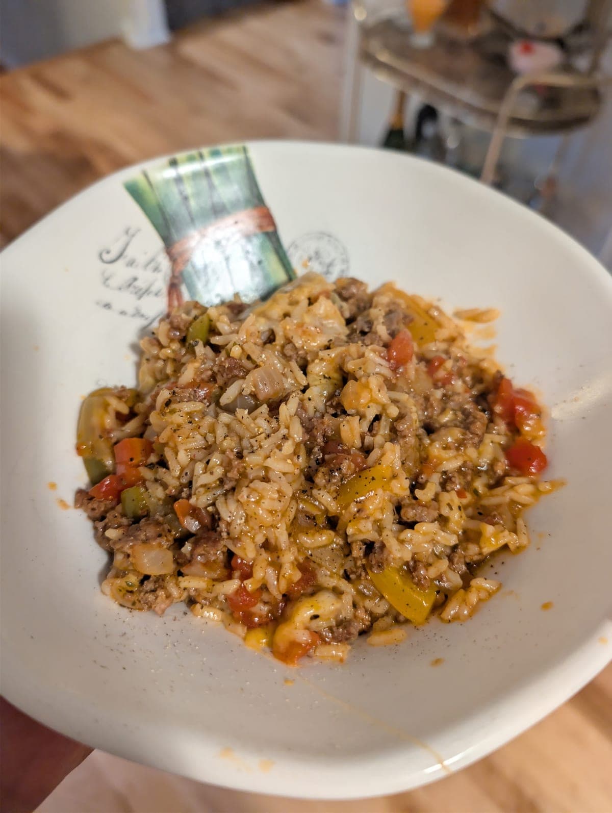 Stuffed pepper skillet in a shallow cream bowl — browned ground beef and rice in a tomatoey sauce, shot through with softened strips of sweet pepper and pieces of tomato, under a heavy grind of black pepper.